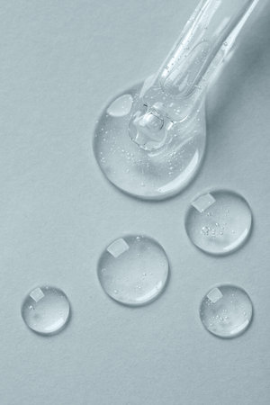 Pipette with cosmetic serum on light background, top view