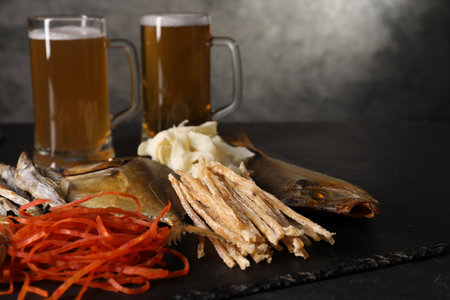 Different dried fish snacks and beer on black table, closeup. Space for textの写真素材