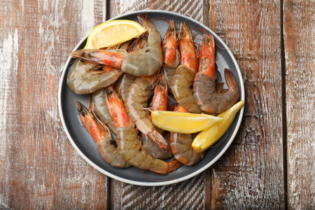 Fresh raw shrimps and lemon on wooden table, top viewの写真素材