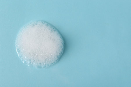 Sample of fluffy foam on light blue background, top view. Space for textの写真素材