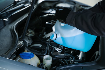 Man pouring windshield washer from plastic canister into car reservoir, closeupの写真素材