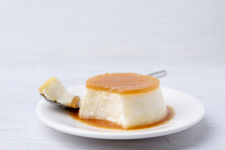 Tasty pudding with caramel sauce served on white textured table, closeup. Space for text