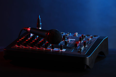 Professional mixing console with microphone on table against dark blue background, closeupの写真素材