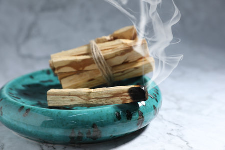 Palo Santo stick smoldering on grey table, closeupの写真素材