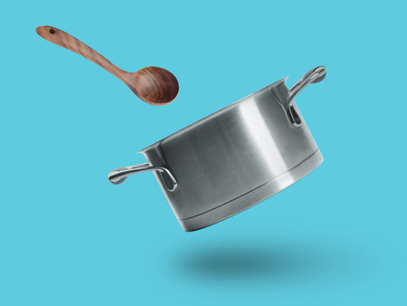 Saucepan and wooden ladle in air on light blue backgroundの写真素材