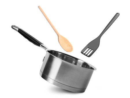 Saucepan, slotted spatula and wooden spoon in air on white backgroundの写真素材