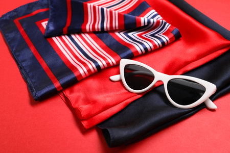 Stylish handkerchiefs and sunglasses on red background, closeupの写真素材