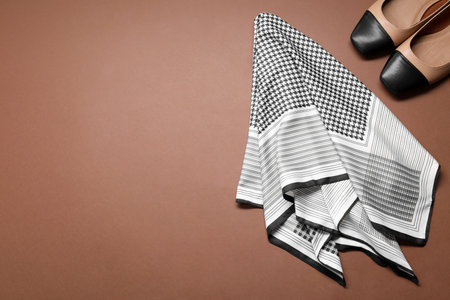 Stylish handkerchief and shoes on brown background, flat lay. Space for textの写真素材