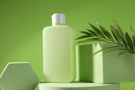 Bottle of sun protection product, branch and podiums against green backgroundの写真素材