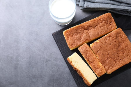 Tasty Japanese Castella sponge cake and milk on grey table, flat lay. Space for text