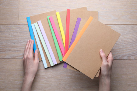 Woman with different copybooks at wooden table, top view
