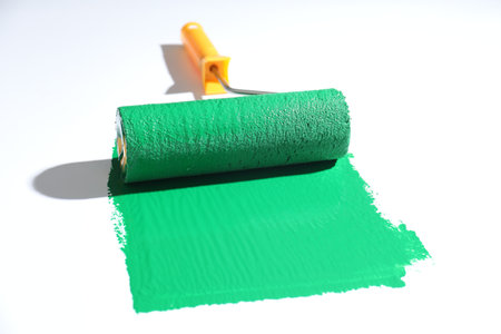 Smear of green paint and roller on white background, closeup