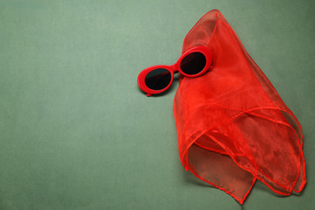 Stylish handkerchief and sunglasses on green background, flat lay. Space for textの写真素材