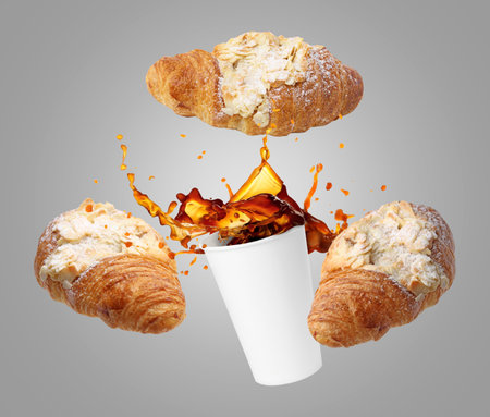 Tasty croissants and freshly brewed coffee. Puff pastry and takeaway cup in air on grey backgroundの写真素材