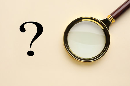 Question mark and magnifying glass on beige background, top viewの写真素材