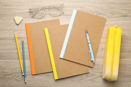 Different copybooks, other stationery and glasses on wooden table, flat layの写真素材