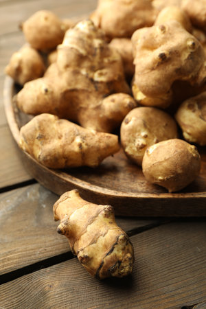 Raw Jerusalem artichokes on wooden table, closeupの写真素材
