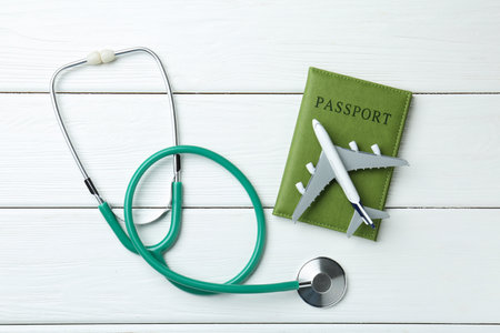 Medical tourism. Stethoscope, plane model and passport on white wooden table, flat layの写真素材