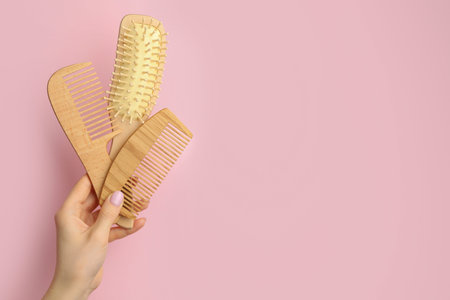 Woman with wooden brush and combs on pink background, closeup. Space for text