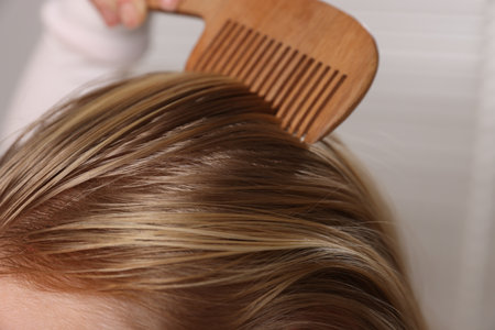 Woman combing her hair on blurred background, closeupの写真素材