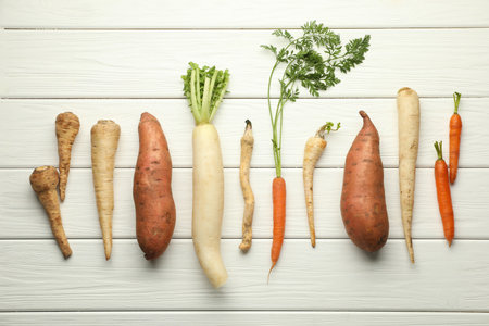 Different root vegetables on white wooden table, flat layの写真素材