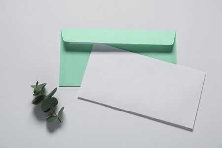 Paper envelope with letter and eucalyptus branch on white background, flat lay. Mockup for designの写真素材