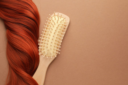 Wooden brush and lock of hair on beige background, top view. Space for textの写真素材