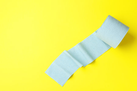 Light blue toilet paper roll on yellow background, top view. Space for textの写真素材