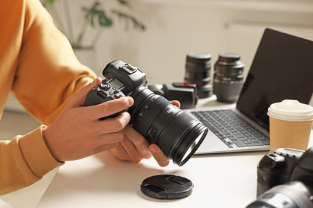 Photographer with professional camera at white desk indoors, closeupの写真素材