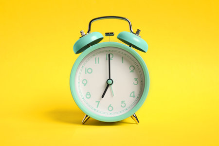 One turquoise alarm clock on yellow backgroundの写真素材