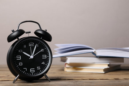 Time for knowledge. Alarm clock and books on wooden table, closeup. Space for textの写真素材