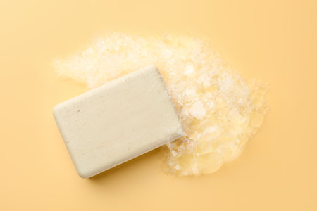 Soap bar with foam on yellow background, top viewの写真素材