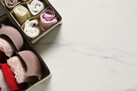 Organizers with different socks and bras on white marble table, flat lay. Space for textの写真素材