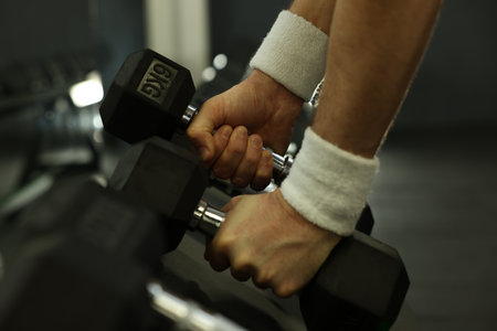 Athletic man training with dumbbells in gym, closeupの写真素材
