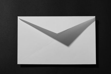 Paper envelope on black background, above view. Mockup for designの写真素材