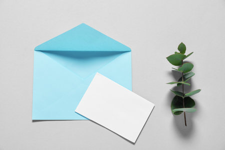 Paper envelope with letter and eucalyptus branch on gray background, flat lay. Mockup for designの写真素材