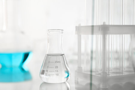 Laboratory glassware on mirror surface against light backgroundの写真素材