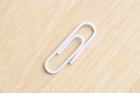 One white paper clip on wooden table, top viewの写真素材