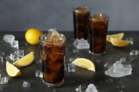 Fresh iced cola and lemon slices on dark grey tableの写真素材