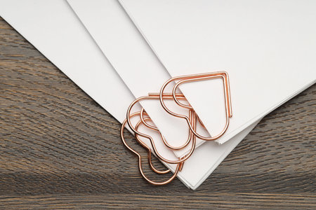 Heart shaped paper clips and notes on wooden table, top view
