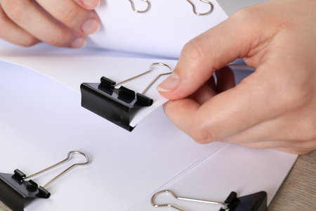 Woman holding sheets of paper with metal binder clips at table, closeupの写真素材