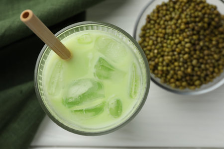Fresh mung bean juice with ice in glass and seeds on white table, flat layの写真素材