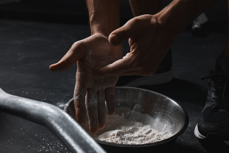 Man applying talcum powder onto his hands above bowl before training with barbell in gym, closeupの写真素材