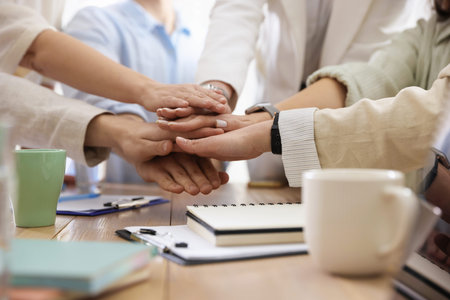 Unity concept. People holding hands together at table indoors, closeup