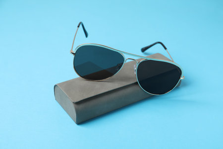 Case with stylish sunglasses on light blue background, closeupの写真素材