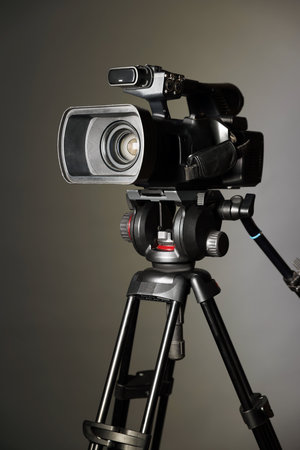 Modern video camera with tripod on gray backgroundの写真素材
