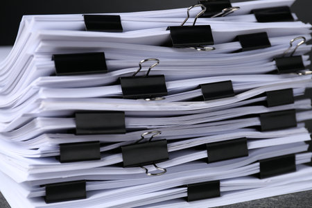 Binder clips with sheets of paper on dark table, closeupの写真素材
