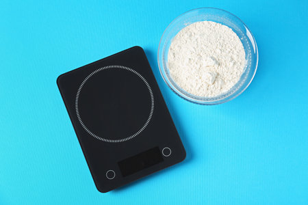 Electronic kitchen scale with flour on light blue background, top viewの写真素材