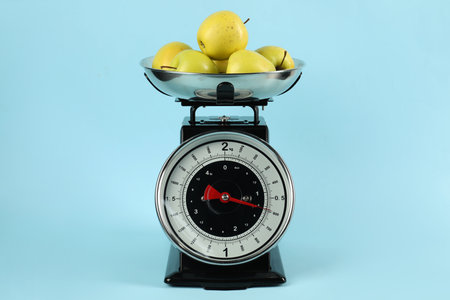 Mechanical kitchen scale with bowl of apples on light blue backgroundの写真素材