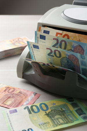 Money counter machine with euro banknotes on white wooden table, closeupの写真素材